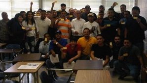 Employees proudly showing their OSHA 10 cards with OSHA trainer Mark A. Hernandez (in orange shirt).