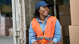Warehouse worker wearing a safety vest near stacked boxes.