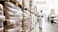 Warehouse Inventory Management and Supply Chain Operations Worker checking inventory in a warehouse aisle.