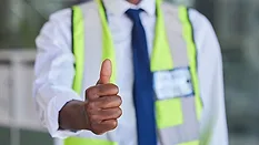 Construction supervisor giving a thumbs-up while wearing a high-visibility safety vest.