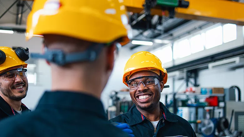Workers wearing hard hats and safety glasses in an industrial facility.