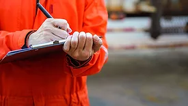 This image depicts a safety officer or construction worker performing a workplace safety audit or inspection