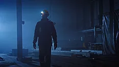 This image captures a scene from a film featuring a industrial worker navigating a dim factory environment. This image captures a scene from a film featuring a industrial worker navigating a dim factory environment.