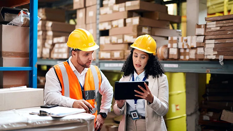 logistics professionals reviewing inventory data on a tablet in a warehouse setting